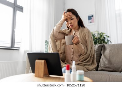 Medicine, Healthcare And Technology Concept - Sick Young Asian Woman Having Video Call Or Online Consultation On Tablet Pc Computer And Drinking Tea At Home