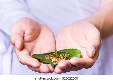 Medicine herb. Herbal pills in hand, palm, fingers with healthy medical plant. Green leaf, alternative drug. Natural pharmaceutical capsule. Vitamin supplement for care, medication