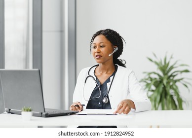 Medicine, Online Service And Healthcare Concept - Happy Smiling African American Female Doctor Or Nurse With Headset And Laptop Having Conference Or Video Call At Hospital