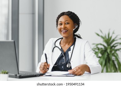 Medicine, Online Service And Healthcare Concept - Happy Smiling African American Female Doctor Or Nurse With Headset And Laptop Having Conference Or Video Call At Hospital