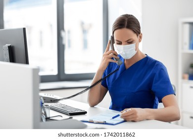 Medicine, People And Healthcare Concept - Female Doctor Or Nurse Wearing Face Protective Medical Mask For Protection From Virus Disease With Computer And Clipboard Calling On Phone At Hospital