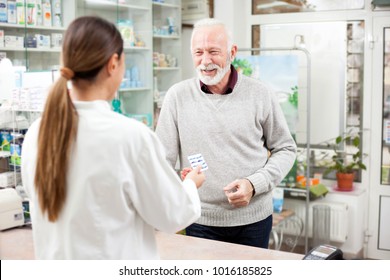 Medicine, Pharmaceutics, Health Care And People Concept - Happy Senior Man Customer Buying Medications At Drugstore