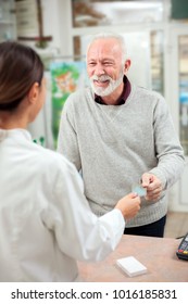 Medicine, Pharmaceutics, Health Care And People Concept - Happy Senior Man Customer Paying For Medications At Drugstore