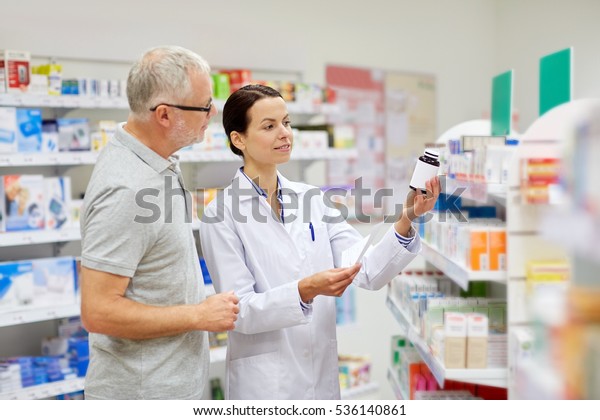 medicine, pharmaceutics, health care and people
concept - happy pharmacist and senior man customer with drug and
prescription at
drugstore