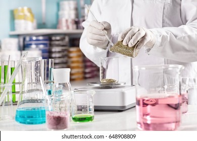 Medicine, pharmacy and cosmetology concept. Unrecognizable scientist manufacturing natural organic healthy cosmetics in laboratory, standing at desk with glass tubes filled with colored liquids