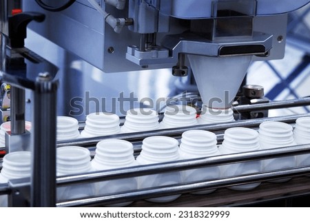 medicine pill capsules are filling in the white plastic bottle on production line machine conveyor at the medical factory.