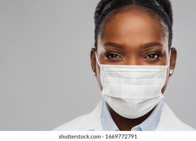 Medizin, Beruf und Gesundheitskonzept - Nahaufnahme von afrikanisch-amerikanischer Ärztin oder Wissenschaftlerin in Schutzmaske auf grauem Hintergrund