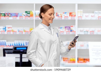 medicine, profession and healthcare concept - happy smiling female doctor with stethoscope using smartphone over pharmacy background