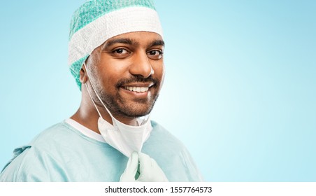 Medicine, Surgery And People Concept - Close Up Of Indian Male Doctor Or Surgeon With Protective Mask Over Blue Background