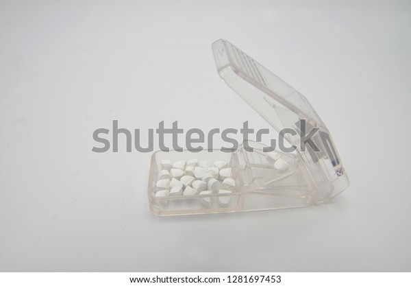 Medicine tablets and a pill cutter. A pill\
cutter is used to split tablets in half and to better adjust the\
proper medicine dose for the patient.\
