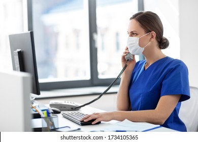 Medicine, Technology And Healthcare Concept - Female Doctor Or Nurse Wearing Face Protective Medical Mask For Protection From Virus Disease With Computer Calling On Phone At Hospital