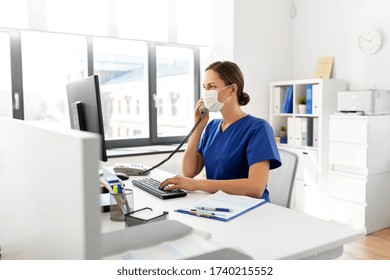 Medicine, Technology And Healthcare Concept - Female Doctor Or Nurse Wearing Face Protective Medical Mask For Protection From Virus Disease With Computer Calling On Phone At Hospital