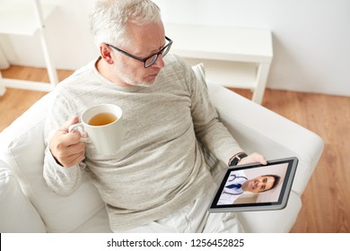 Medicine, Technology And Healthcare Concept - Senior Man Having Video Call With Male Doctor On Tablet Pc Computer And Drinking Tea At Home