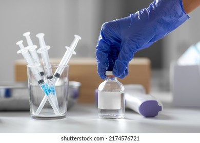 medicine, vaccination and healthcare concept - close up of syringes and hand in glove opening medicine or jar with vaccine