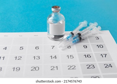 Arzneimittel, Impfung und Gesundheitskonzept - Einwegspritze und Kalender auf blauem Hintergrund