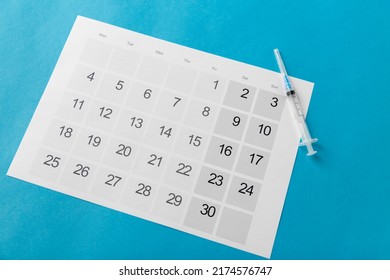 Arzneimittel, Impfung und Gesundheitskonzept - Einwegspritze und Kalender auf blauem Hintergrund