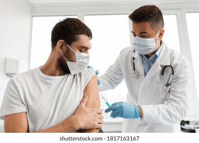 Medicina, vacunación y atención de la salud - médico que lleva una máscara médica protectora facial para la protección frente a la enfermedad viral con una jeringa que inyecta la vacuna a un paciente varón