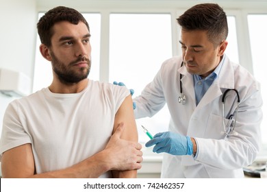 medicine, vaccination and healthcare concept - doctor with syringe doing injection of vaccine to male patient