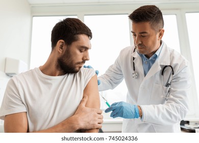medicine, vaccination and healthcare concept - doctor with syringe doing injection of vaccine to male patient