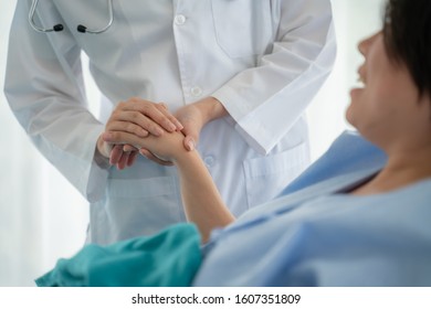 Medicine,health care and trust concept.Doctor holds the hand of a patient as a sign of care and consolation.Hand of doctor reassuring his female patient in bed at hospital. - Shutterstock ID 1607351809