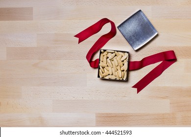 Medicine,Pills In The Open Silver Gift Box And Red Ribbon On Wood Texture Office Desk Or Table View From Top Or Above.Copy Space On The Left Down