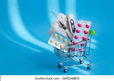 Medicines And Pills In A Shopping Cart  On Blue Background. Consumer Buying Panic About Coronavirus Covid-19 Concept.  First Aid Kit For Home Quarantine. Drug Delivery. Copy Space.