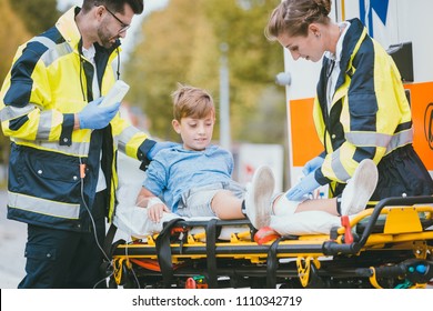 Medics putting injured boy on stretcher after accident in front of ambulance car - Powered by Shutterstock