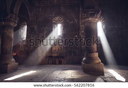 Medieval Armenian christian church interior with sun rays from the window falling on the candles. Religion, old architecture, christianity, travel, belief concept.