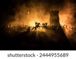 Medieval battle scene with cavalry and infantry. Silhouettes of figures as separate objects, fight between warriors on dark toned foggy background. Night scene. Selective focus