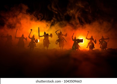 Medieval battle scene with cavalry and infantry. Silhouettes of figures as separate objects, fight between warriors on dark toned foggy background. Night scene. Selective focus - Shutterstock ID 1043509663
