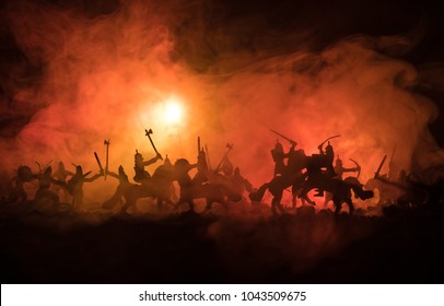 Medieval battle scene with cavalry and infantry. Silhouettes of figures as separate objects, fight between warriors on dark toned foggy background. Night scene. Selective focus - Shutterstock ID 1043509675