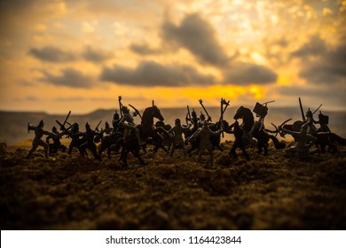 Medieval battle scene with cavalry and infantry. Silhouettes of figures as separate objects, fight between warriors on sunset foggy background. Selective focus - Shutterstock ID 1164423844