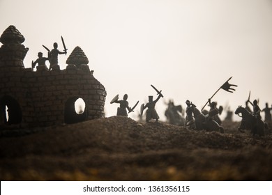 Medieval battle scene with cavalry and infantry. Silhouettes of figures as separate objects, fight between warriors on sunset foggy background. Selective focus - Shutterstock ID 1361356115