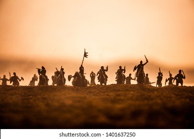 Medieval battle scene with cavalry and infantry. Silhouettes of figures as separate objects, fight between warriors on sunset foggy background. Selective focus - Shutterstock ID 1401637250