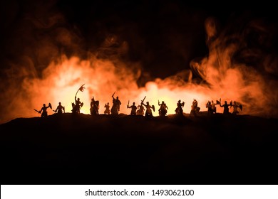 Medieval battle scene with cavalry and infantry. Silhouettes of figures as separate objects, fight between warriors on dark toned foggy background with medieval castle. Selective focus