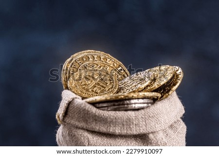 Medieval coins in an old rag bag close-up. Achieving financial goals concept, selective focus, low shallow focus