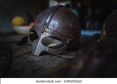 Medieval helmet and glove on a wood table. Armor of middle-ages, knightly equipment, armory forge. Vanitas still life.
