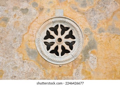 Medieval italian stone rose window against a plaster wall - Italy