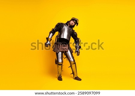 Medieval knight in full armor posing against bright yellow background