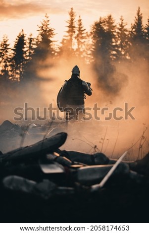 Medieval Knight Walking on Battlefield amidst Dead Enemies. Surviving Crusader, Soldier, Warrior after Battle. Smoke and Destruction of War, Invasion, Crusade. Dramatic, Cinematic Historic Reenactment