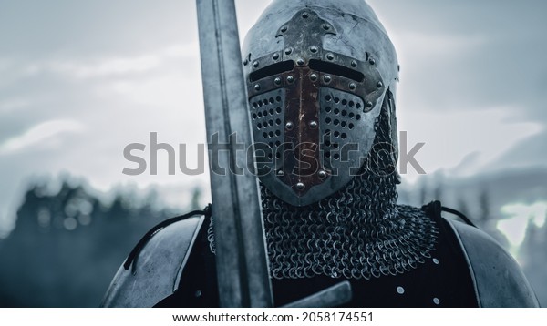 Medieval Knight Wearing Armour and Helmet,\
Draws Sword from Shearh, Ready to Fight, Kill His Enemy in Battle.\
Warrior Soldier on Battlefield. War, Invasion, Crusade. Cinematic\
Historic Reenactment