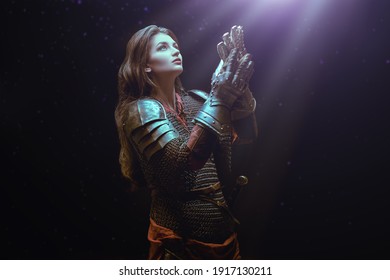 Medieval knight woman in armor prays, blessing before the battle.