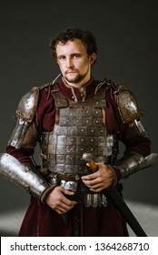 Medieval Man Knight In Armor And Weapon On Dark Background. Portrait Of The Knight