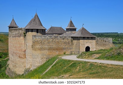 Medieval old fortress castle with ancient stone walls, wooden roofs and road, green hills and clear blue sky, Khotyn, Ukraine - Shutterstock ID 1015247173