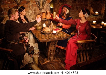 Medieval people eat and drink in ancient castle tavern.