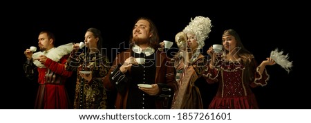 Medieval people as a royalty persons in vintage clothing drinking coffee, tea on dark background. Concept of comparison of eras, modernity and renaissance, baroque style. Creative collage.