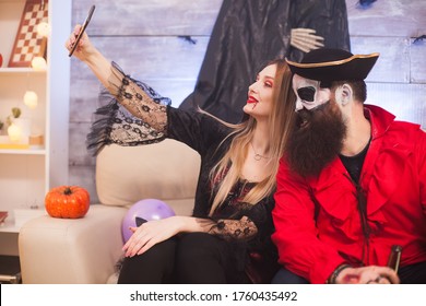 Medieval Pirate Winking While Vampire Woman Taking A Selfie At Halloween Party.