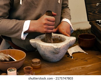 medieval reenactment - herbalist table person grinds seeds with mortar and pestle to create a dough - Powered by Shutterstock