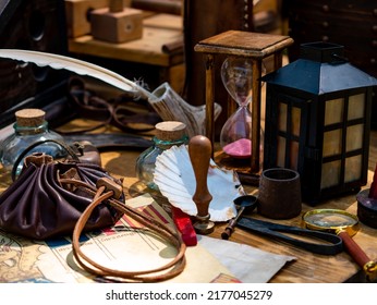 medieval reenactment - scribe's table with goose feather pen, hourglass, sealing wax stamp on a table