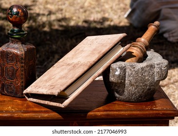 Medieval Reenactment - Stone Mortar And Pestle On A Wooden Table With A Book